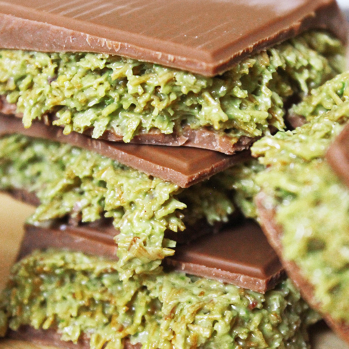 Close-up of Ceres Gourmet Dubai Chocolate Pistachio Bar 3.5 Oz Square shows green pistachio and coconut layers inside smooth milk chocolate—a luxury Middle Eastern dessert or Halloween chocolate gift.