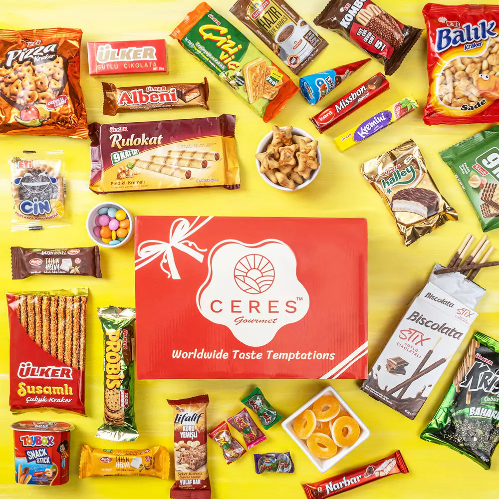 A vibrant yellow background highlights a red Ceres Gourmet 50-Pack International Snack Box—Assorted Treats, surrounded by colorful international snacks, chocolates, and biscuits—perfect for employee appreciation or corporate gifting.