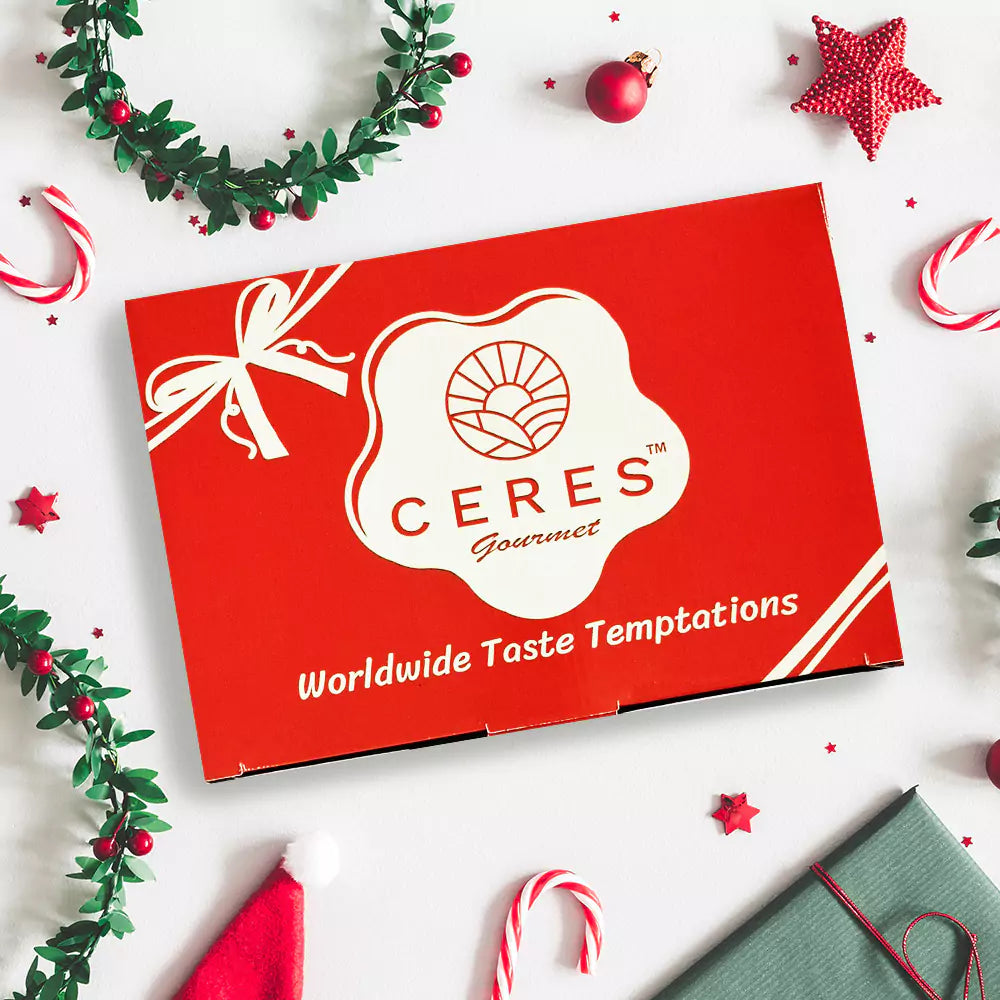A Ceres Gourmet 50-Pack International Snack Box - Assorted Treats with a white ribbon design and the slogan Worldwide Taste Temptations, surrounded by festive décor—ideal for employee appreciation.