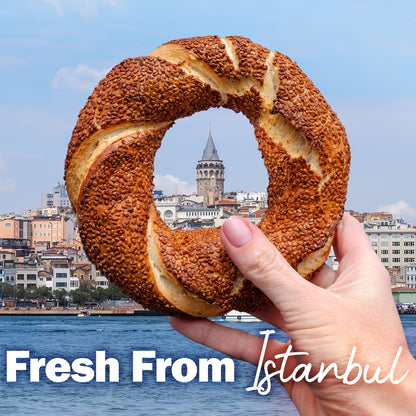 Hand holding a sesame seed bagel with Istanbul's Galata Tower in the background