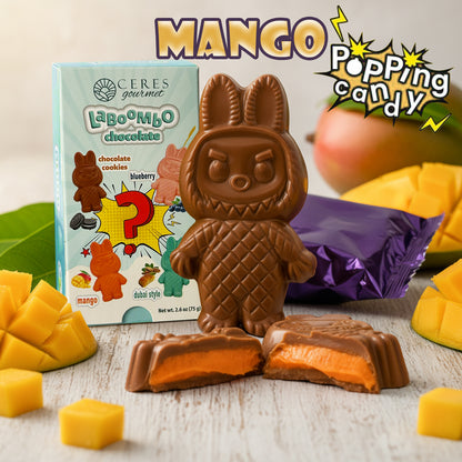 Chocolate tiki figure with mango popping candy, Ceres La Boom Ho chocolate packaging, and mango pieces on a wooden surface.