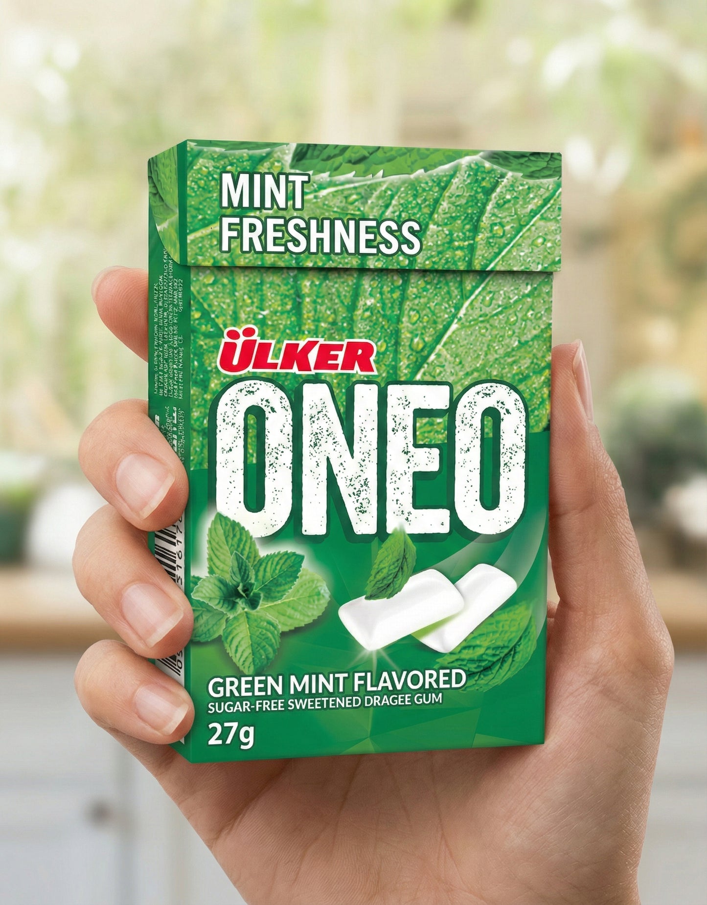 Green box of Ulker ONEO green mint flavored gum held by a hand with a blurred background