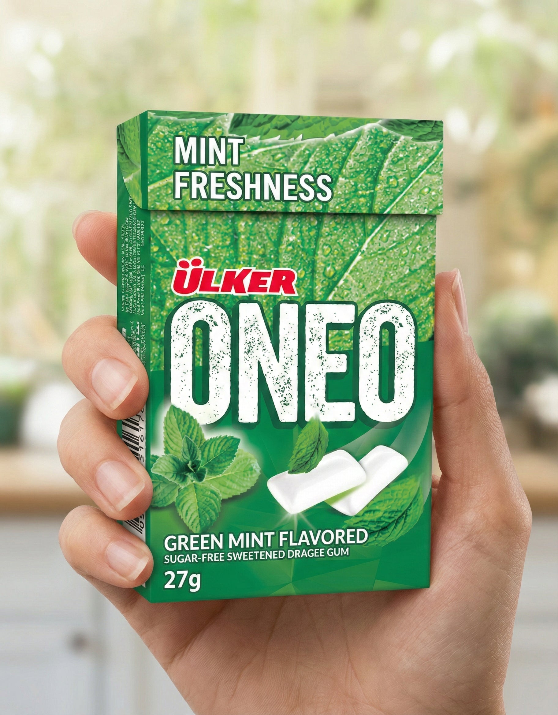 Green box of Ulker ONEO green mint flavored gum held by a hand with a blurred background