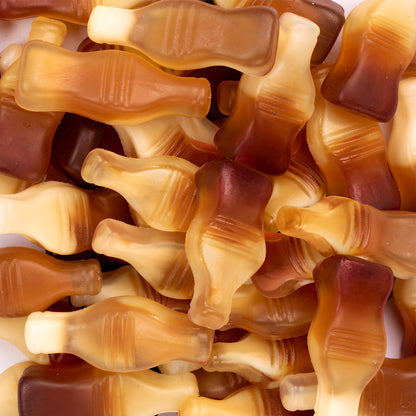 Close-up of gummy candy shaped like bottles in brown and beige colors.