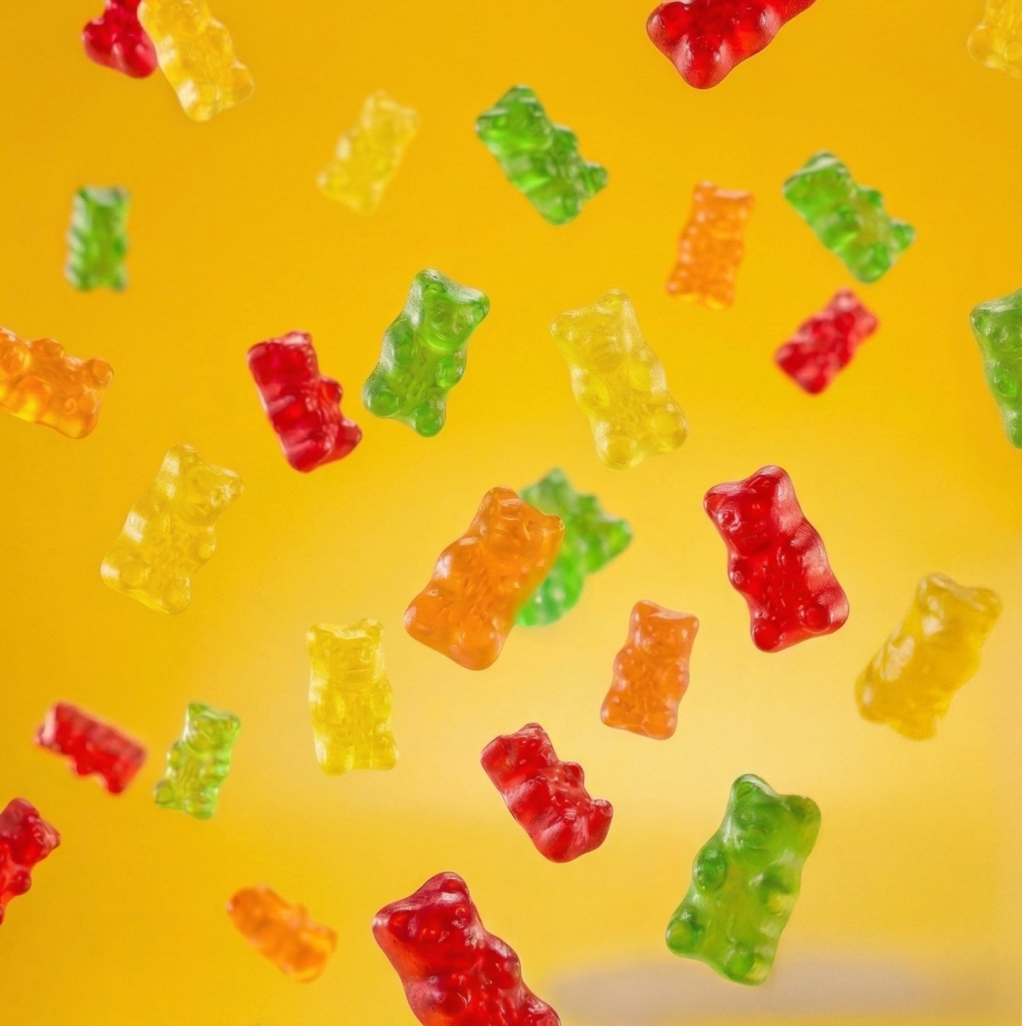 Colorful gummy bears on a yellow background