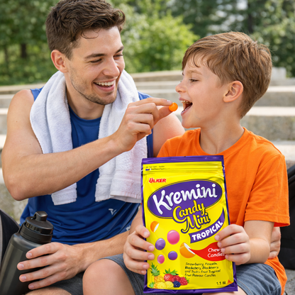 Man feeding a child a candy, with a Kremini Candy Mix packet in the foreground.