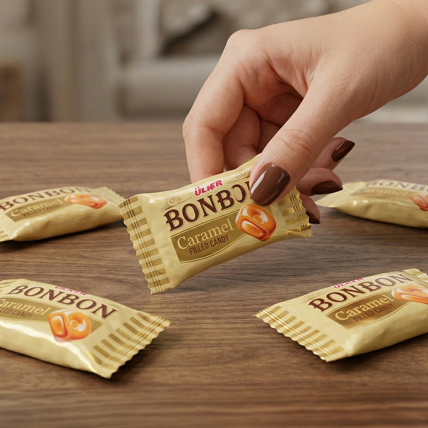 Hand holding a Bonbon Caramel candy wrapper on a wooden table with other candy wrappers.