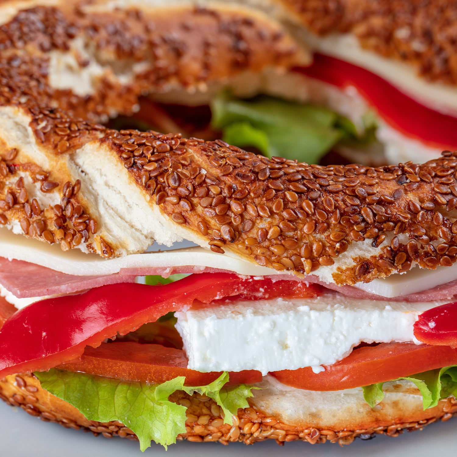 Bagel sandwich with ham, cheese, and tomato on a sesame seed bagel.