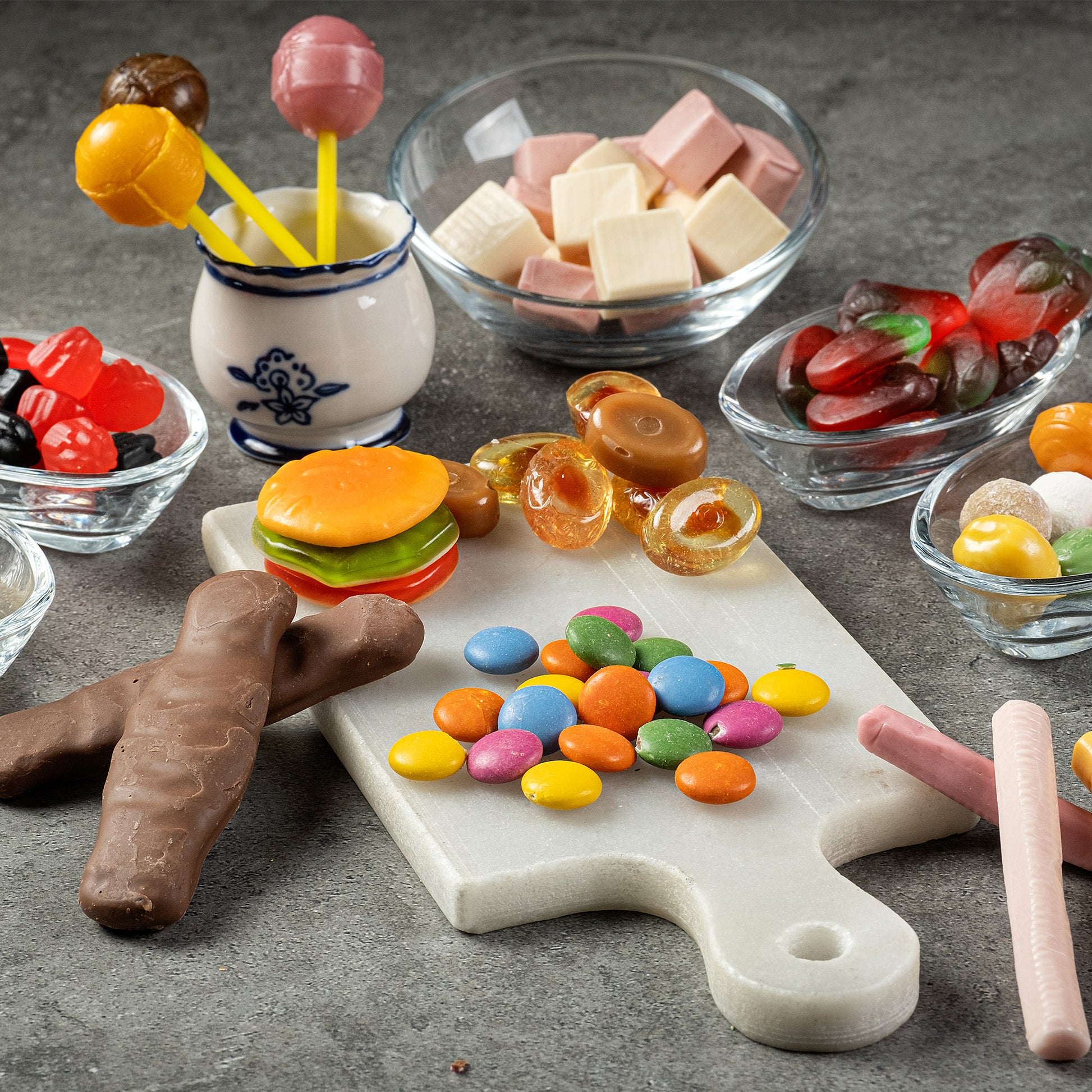 The Ceres Gourmet Candy Snacks Box features 40 rare and unique foreign candies, including chocolate bars, gummies, and lollipops, attractively arranged on a marble board and in small glass bowls.