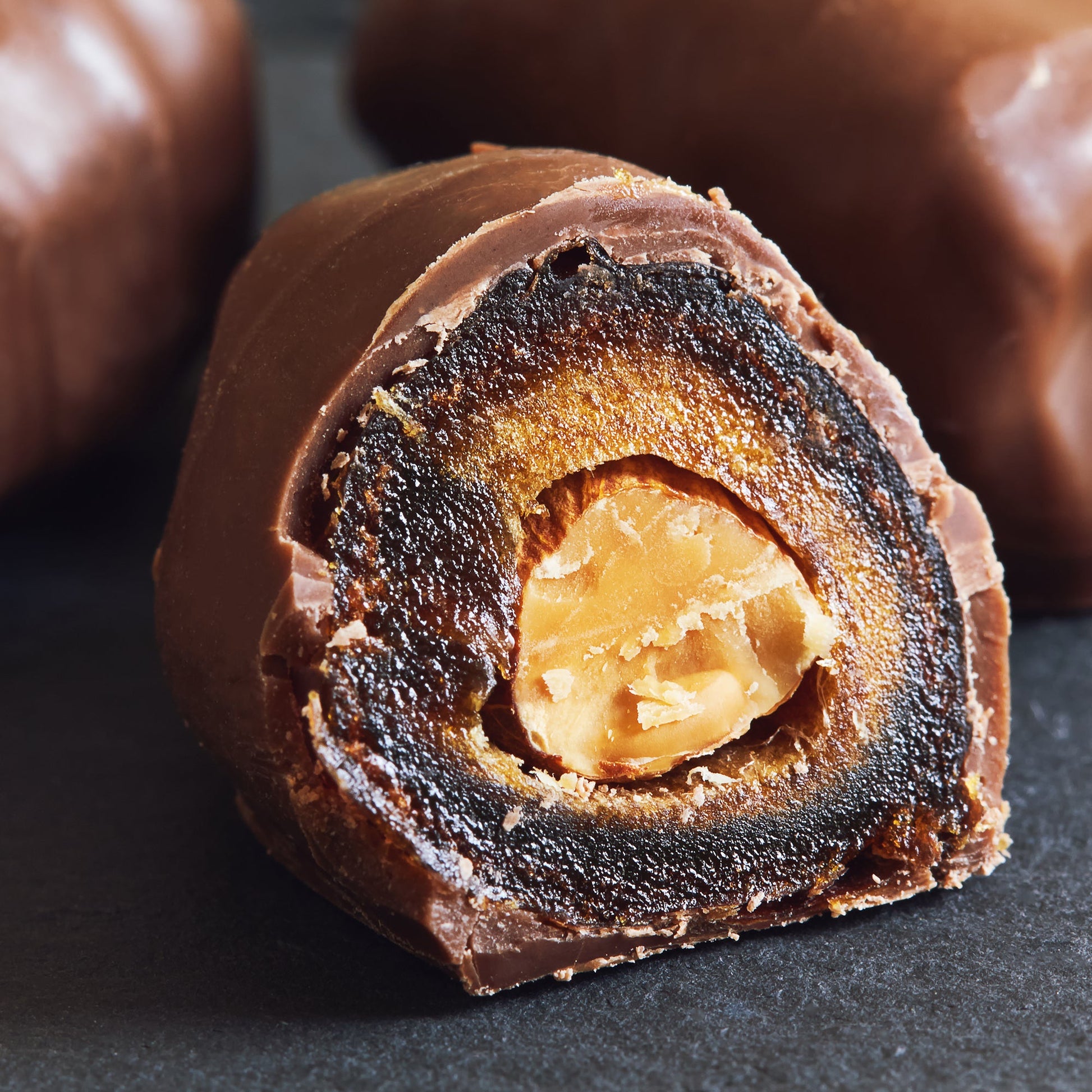 Close-up of Ceres Gourmet Dark Chocolate Coated Medjool Dates Stuffed with Almonds, cut to show the almond center, surrounded by glossy chocolate—delicious and healthy, available in 2 packs (8.46 oz).