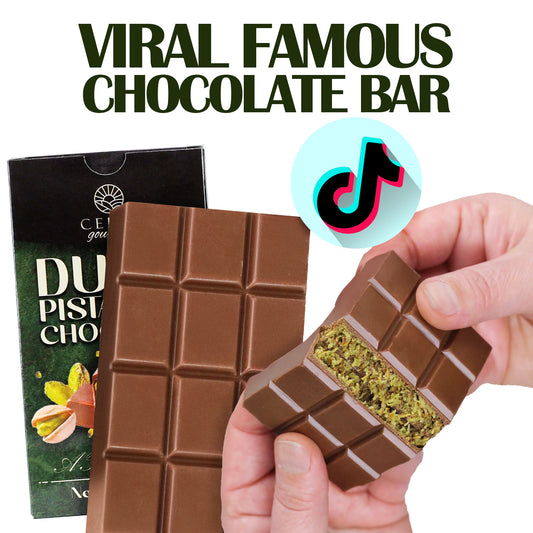 A hand breaks a Ceres Gourmet Dubai Chocolate Bar (2.3 oz), revealing its green filling. The box and TikTok logo appear behind, with bold “VIRAL FAMOUS CHOCOLATE BAR” above—try this trending treat in 3-12-24 packs!.
