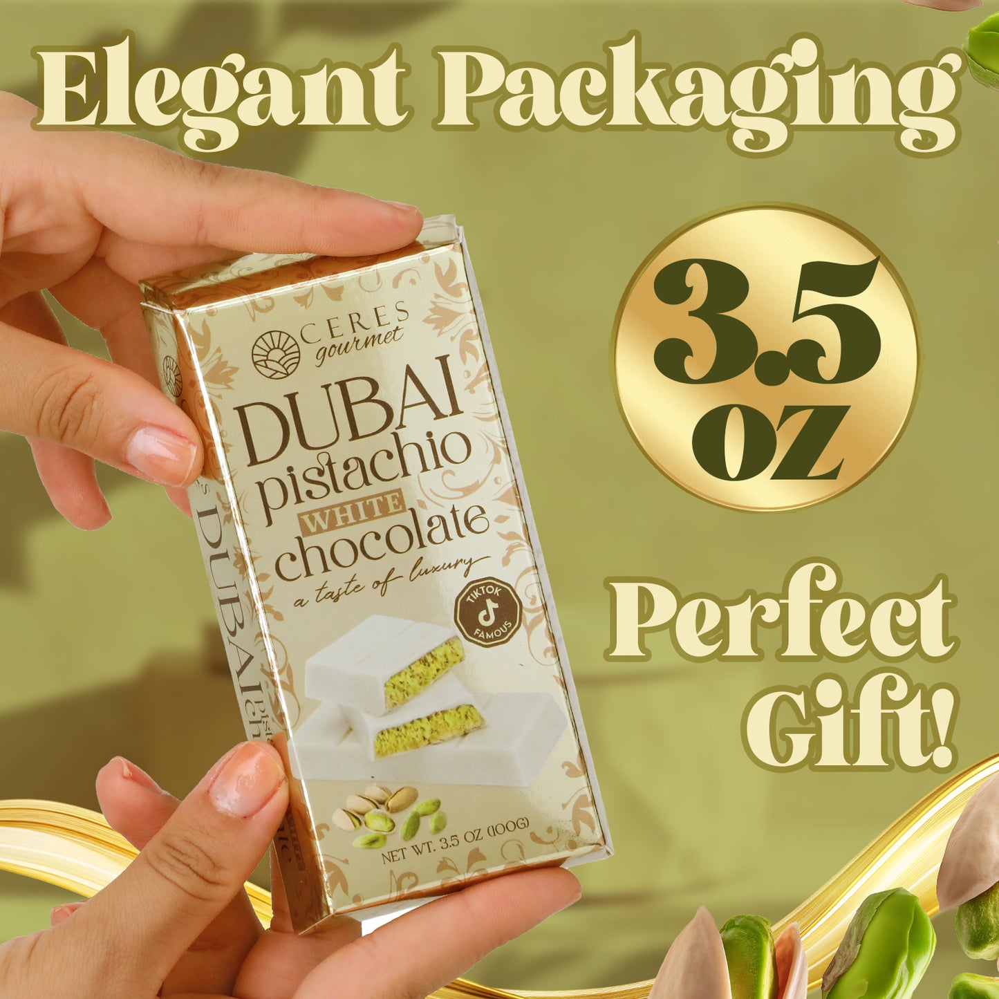 A hand holds a Ceres Gourmet Dubai Chocolate Bar Pistachio with White Chocolate & Knafeh, 3.5 oz. Elegant packaging and a gold-themed background with pistachios highlight this perfect gift and exquisite chocolate delight.
