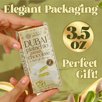 A hand holds a Ceres Gourmet Dubai Chocolate Bar Pistachio with White Chocolate & Knafeh, 3.5 oz. Elegant packaging and a gold-themed background with pistachios highlight this perfect gift and exquisite chocolate delight.