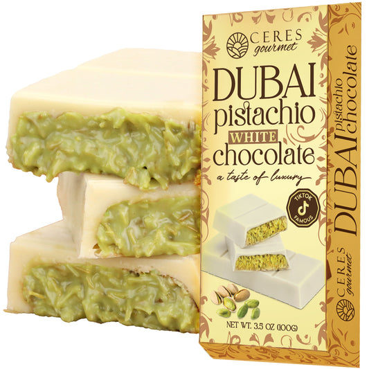 A stack of Ceres Gourmet Dubai Chocolate Bar Pistachio with White Chocolate & Knafeh (3.5 oz) sits beside its box, which showcases images and descriptions of chocolate, pistachios, and kunafa on the packaging.