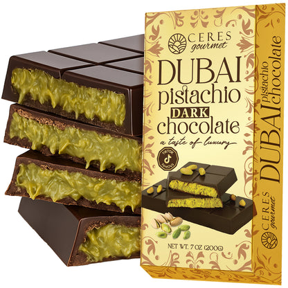 A box of Ceres Gourmet Dark Chocolate Dubai Crispy Knafeh Pistachio Bar 7oz is displayed beside pieces filled with creamy pistachio. The packaging highlights luscious dark chocolate and knafeh pistachios.