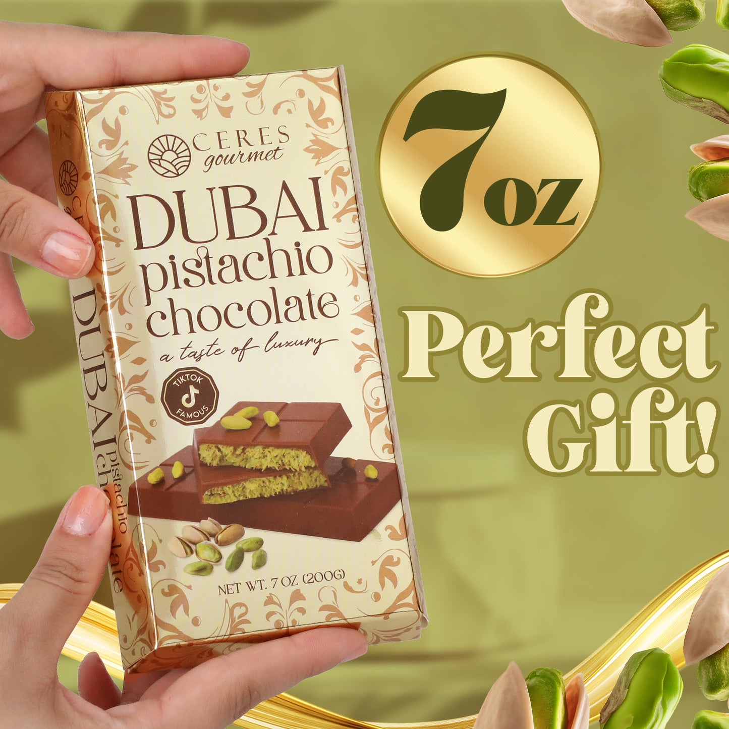 A hand holds a 7oz Ceres Gourmet Dubai Chocolate Kunafa Pistachio Indulge in the Irresistible Delight Bar, inspired by Middle Eastern desserts, set against a green background with pistachios and bold gold text: “7 oz Perfect Gift!”.