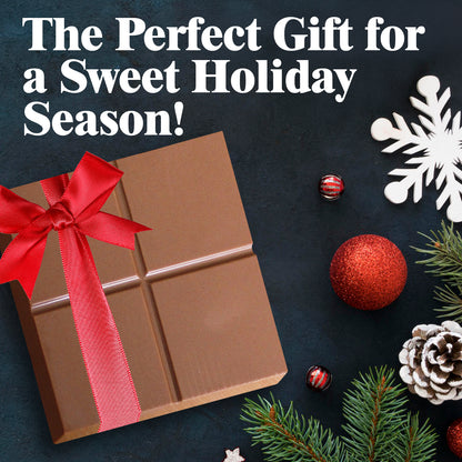 A festive flat lay features the Ceres Gourmet Dubai Chocolate Pistachio Bar 3.5 Oz Square, Luxury Halloween Chocolate, gift wrapped in red ribbon and surrounded by pine branches, red ornaments, decorative balls, and a white snowflake—a gourmet holiday treat.