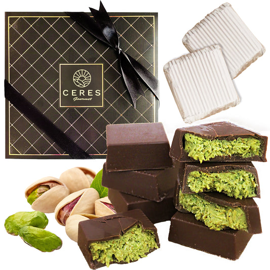 A Ceres Gourmet Dubai Knafah Pistachio Chocolate Bar gift box with 16 exquisite bite-sized chocolates, garnished with scattered pistachio nuts and tied with a black ribbon.