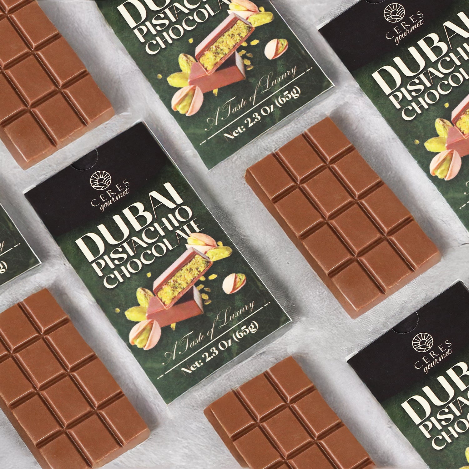 Flat lay of several unwrapped Ceres Gourmet Dubai Chocolate Bar 3-12-24-Pack, 2.3 oz (65g) each, and their pistachio-themed wrappers on a light surface, highlighting both the chocolate bars and vibrant packaging.