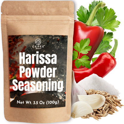 A pouch of Ceres Gourmet Harissa Seasoning Blend, 3.5 oz, Aromatic & Mildly Spicy Harissa Powder sits beside fresh red chili peppers, parsley, garlic cloves, cumin seeds, and salt, highlighting this bold North African spice mix.