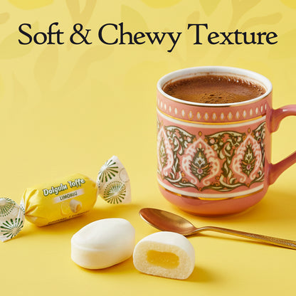 Decorative mug with hot beverage, soft chewy treats, and a spoon on a yellow background.