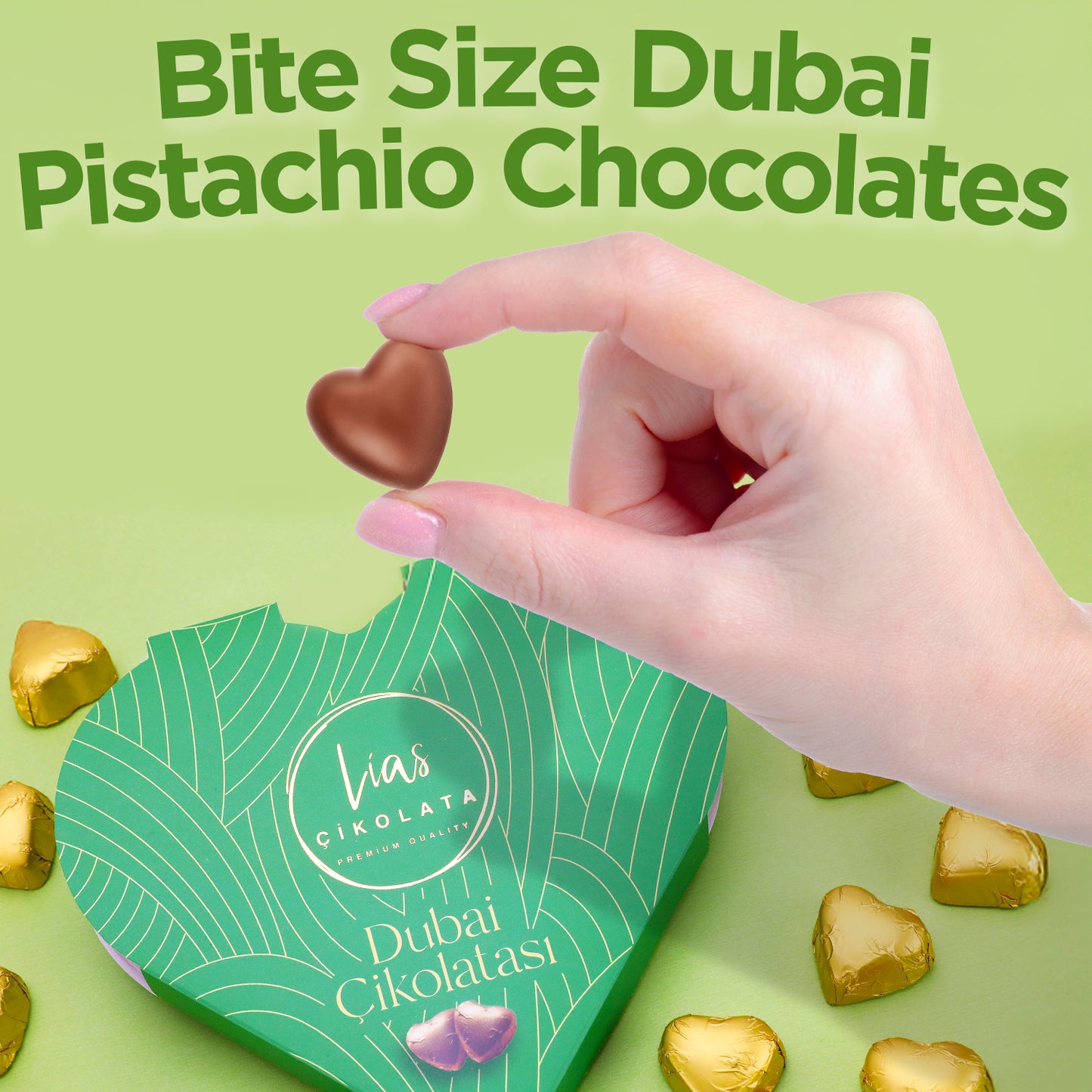 A hand holds a heart-shaped chocolate above a green Ceres Gourmet box labeled Love Bite Dubai Chocolate Pistachio, 10 Bite-Size Pieces. Gold-wrapped hearts surround the box. Text reads: Bite Size Dubai Pistachio Chocolates.