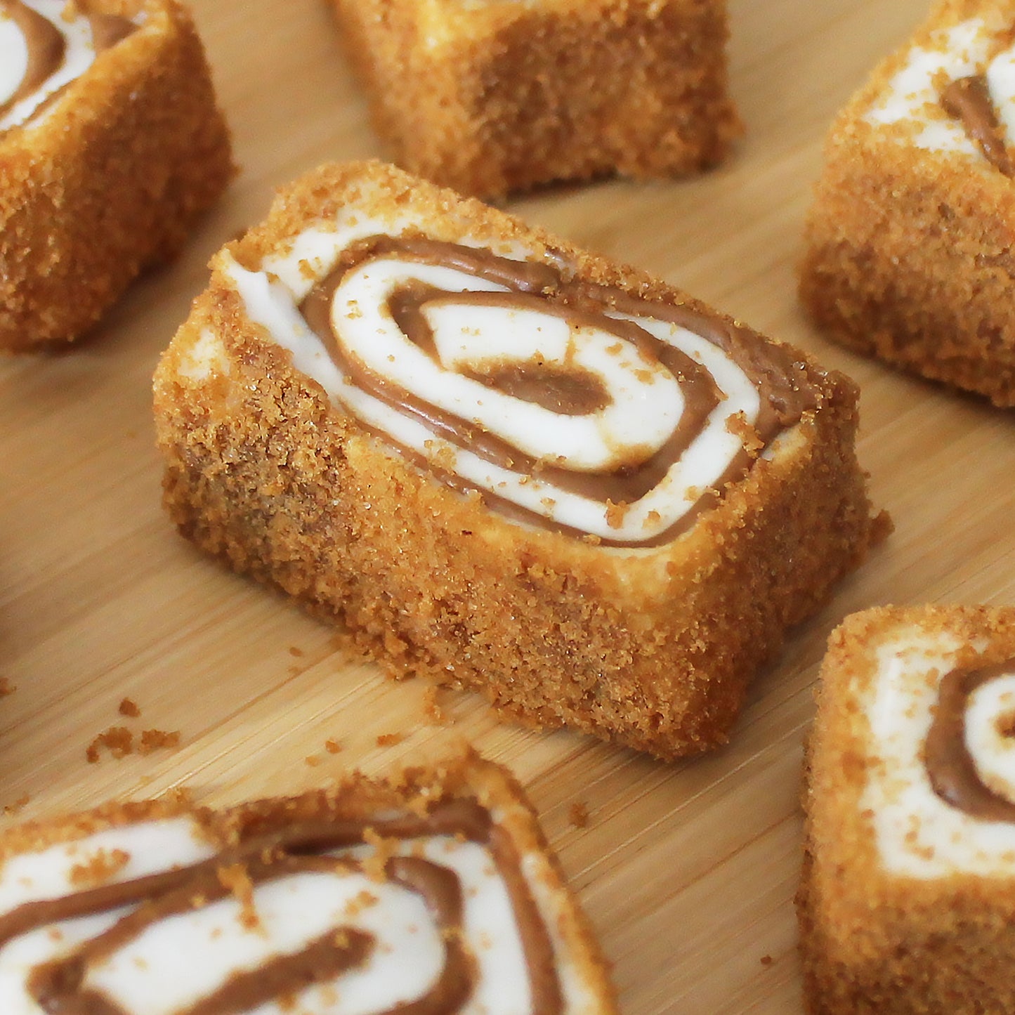 Close-up of Ceres Gourmet Turkish Delight Candy Authentic Sweets Lokum, Oreo & Lotus flavored, featuring rectangular bars with a crumbly golden crust and swirled cream-chocolate filling, arranged on a wooden surface.