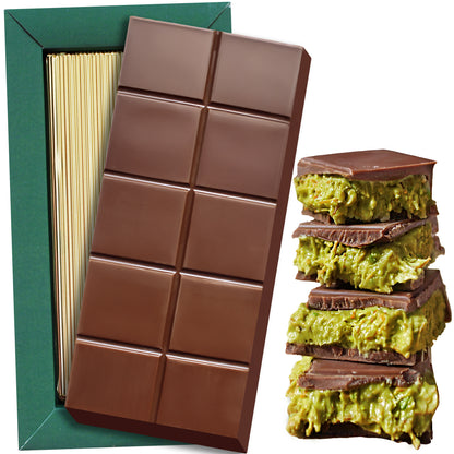 The Ceres Gourmet Special Viral Dubai Chocolate Pistachio Bar 7oz sits atop its elegant green and gold box, next to a stack of chocolate pieces with creamy pistachio filling.