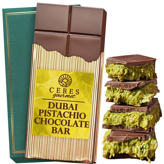 A Special Viral Dubai Chocolate Pistachio Bar 7oz with Elegant Box by Ceres Gourmet, partially unwrapped to show chocolate squares, rests next to a stack of chocolate pieces filled with green pistachio and kunafa.