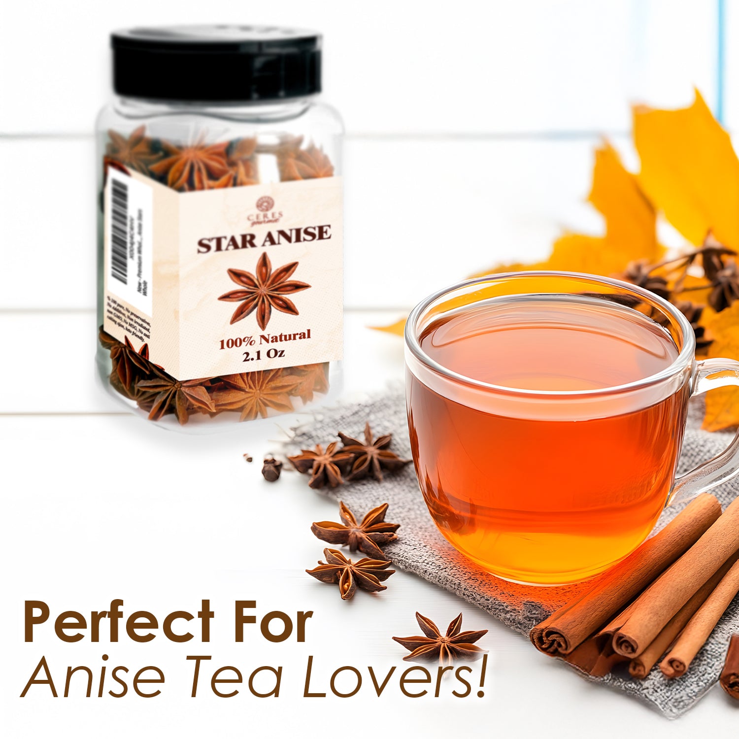 A clear Ceres Gourmet Whole Star Anise Pods 2.1 oz jar sits by orange herbal tea, with star anise and cinnamon sticks nearby amid yellow autumn leaves. Ideal for baking, cooking, or making fragrant anise tea!.